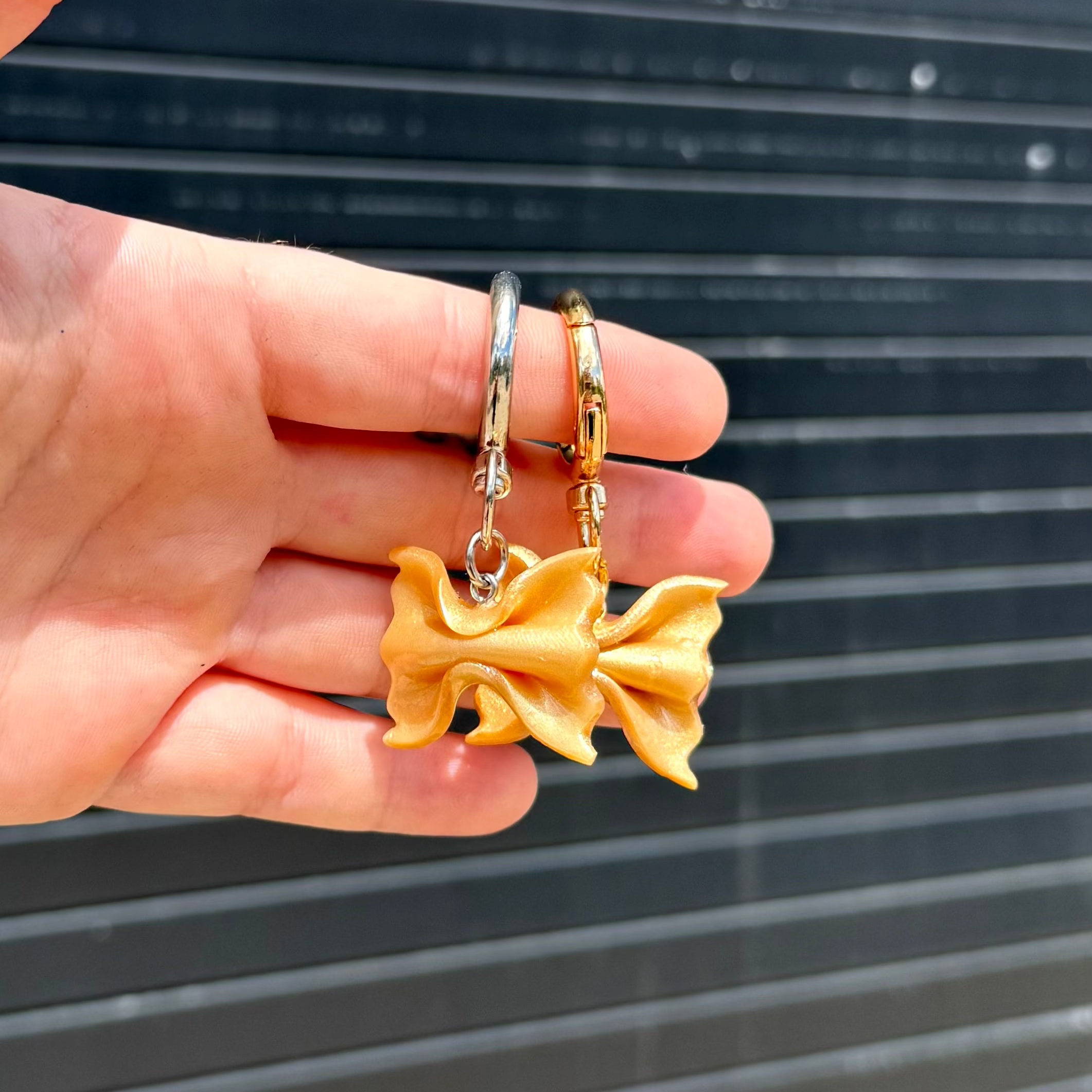 gold shimmery pasta keychains shaped into bowties. 