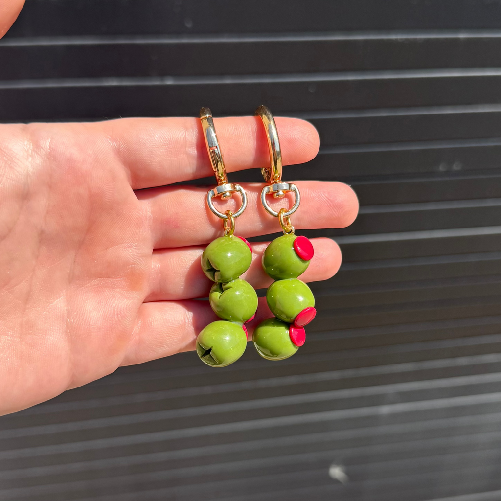 three polymer clay green olives stacked on top of each other dangling from a keychain.